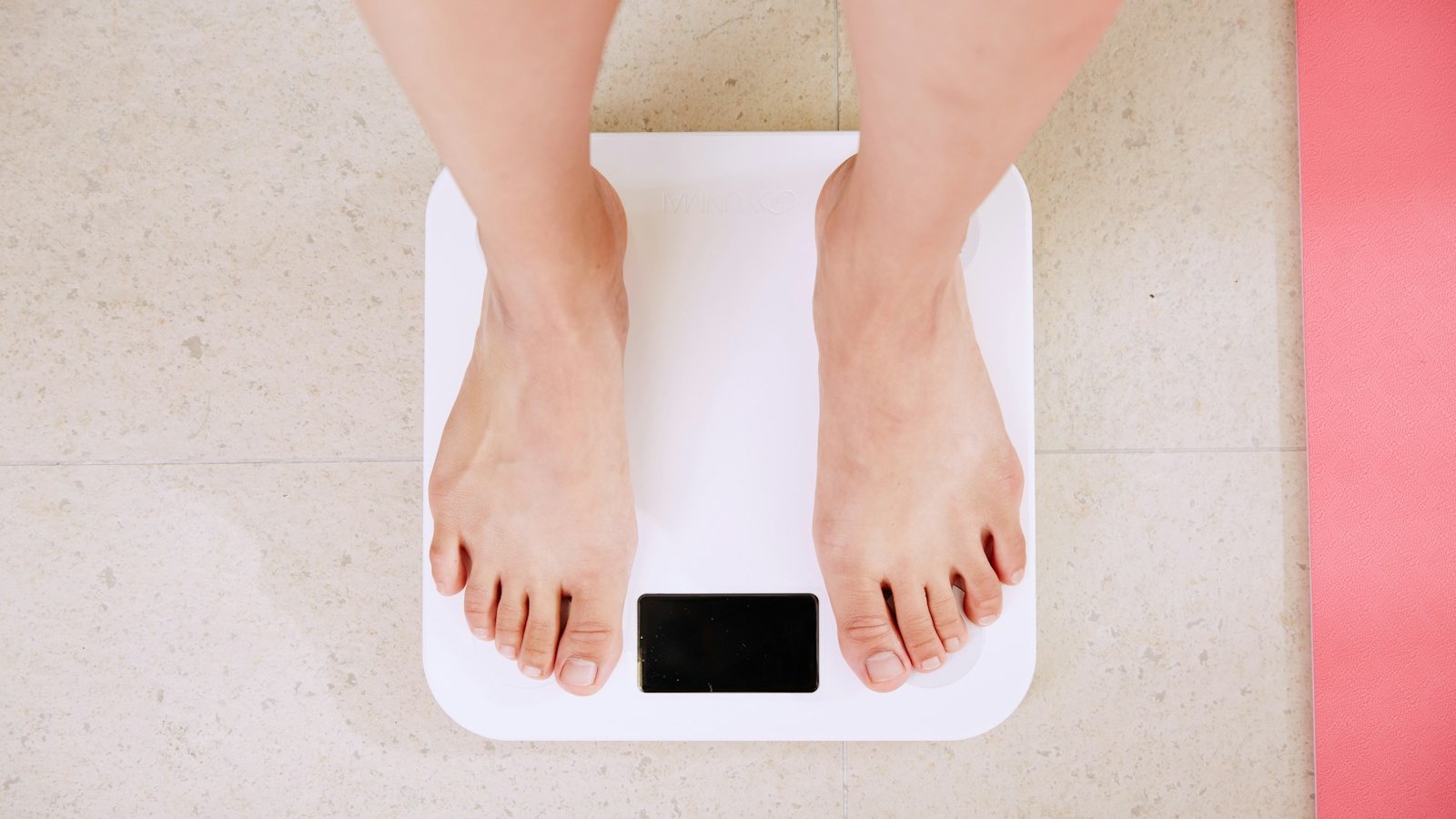 Person standing on a digital scale while tracking weight loss progress
